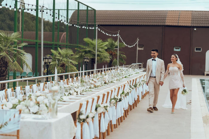 A wedding couple walking next to a beautiful set table, looking happy and calm.